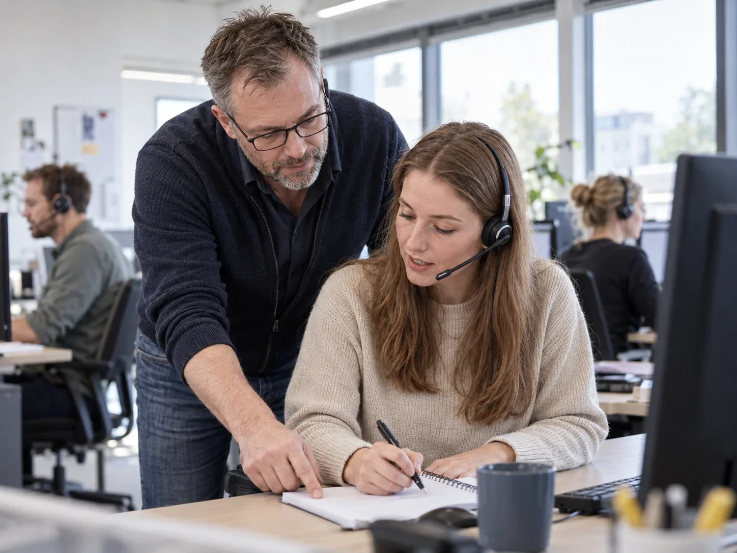 Zwei Kolleginnen und Kollegen von starbuero.de am Arbeitsplatz, eine davon mit Headset am Telefon