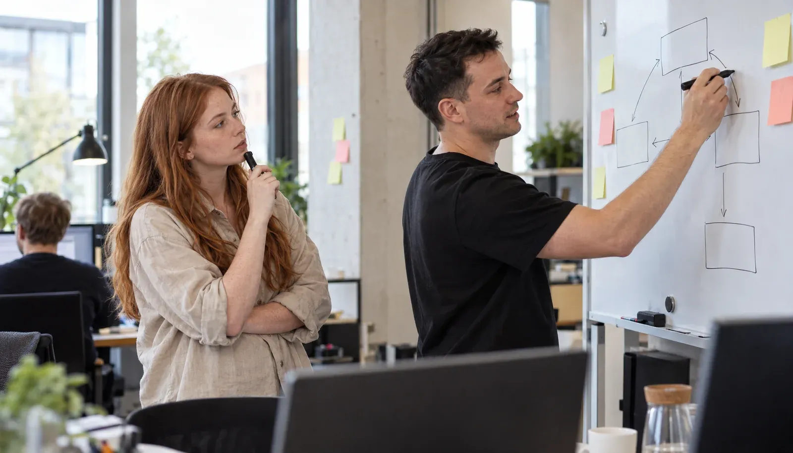 Gründer zeichnet am Whiteboard, seine Mitgründerin denkt mit