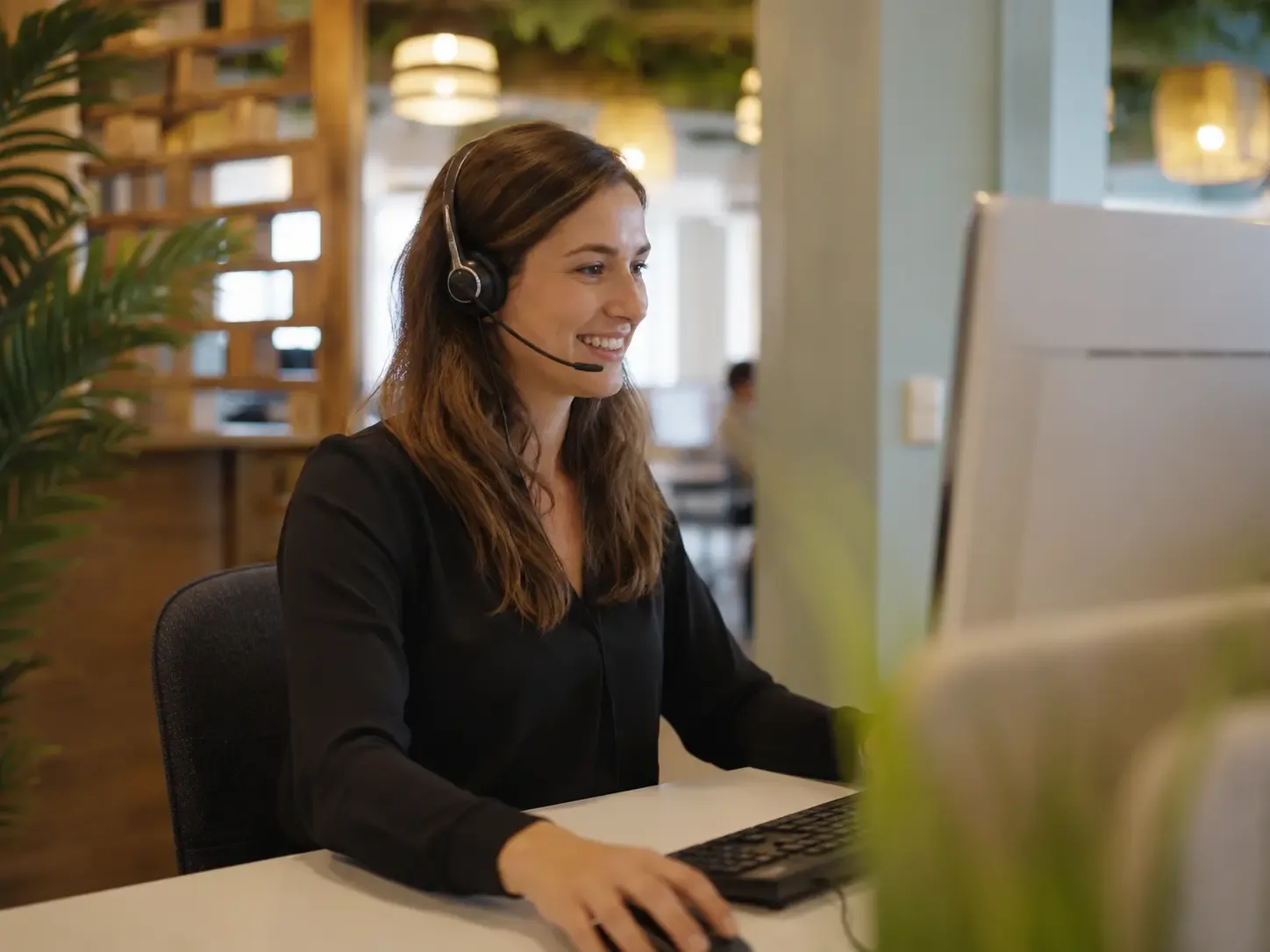 Mitarbeiterin von starbuero.de nimmt mit Headset am Schreibtisch einen Kundenanruf entgegen
